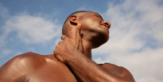 modelo masculino sujetando su cuello y mirando hacia arriba